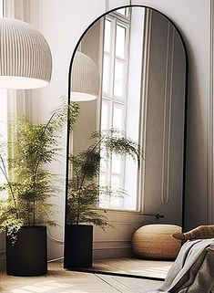 a mirror sitting on top of a wooden floor next to a potted plant in front of a window