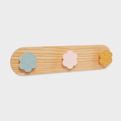 three flower shaped wooden pegs on top of a piece of plywood wood with four different colors