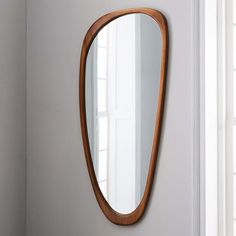 a wooden mirror hanging on the wall next to a white door and window sill