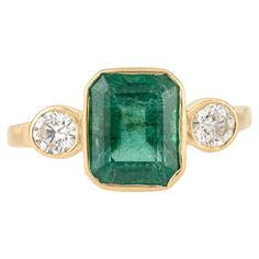 an emerald and diamond ring with three diamonds