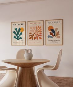 a table with two vases on top of it in front of three framed pictures