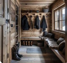 the inside of a wooden cabin with boots and coats hanging on the wall next to it