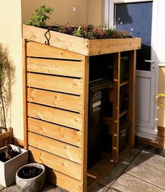 a wooden planter with plants growing out of it's sides on the side of a house