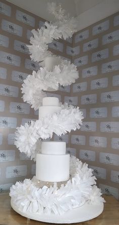 a three tiered white cake sitting on top of a table next to a wall