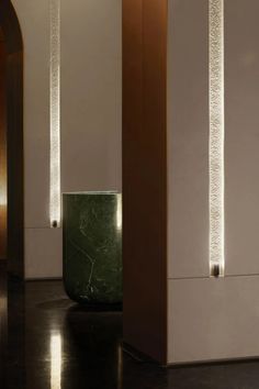 a large green vase sitting in the middle of a room next to two tall white pillars