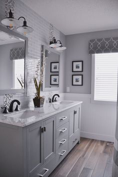 a large bathroom with two sinks, mirrors and pictures on the wall above it's countertop