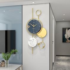 a clock on the wall next to a plant in a room with white walls and flooring