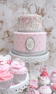 there are many cupcakes and cakes on this cake stand with pink frosting