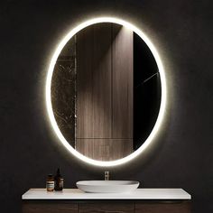 a bathroom sink under a round mirror with lights on it's sides and a wooden cabinet underneath