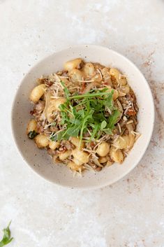 a white bowl filled with food sitting on top of a marble counter next to a knife and fork