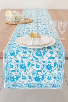 a blue and white table runner with two cookies on it, along with wine glasses