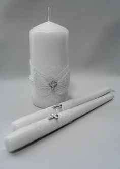 a white candle with a cross on it next to a pair of crochet hooks