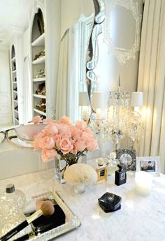 a bathroom vanity with pink roses in a vase and other items on the counter top