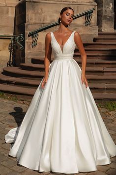 a woman in a white wedding dress standing on some steps with her hand on her hip