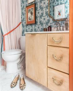 a bathroom with blue wallpaper and wooden cabinetry next to a white porcelain toilet