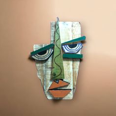 a piece of art that looks like a face with green hair and blue eyes is hanging on the wall