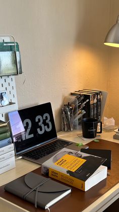 an open laptop computer sitting on top of a wooden desk next to a stack of books