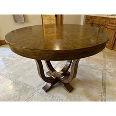 a wooden table sitting on top of a tile floor next to a dresser and cabinets