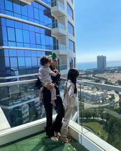 two women and a child standing on top of a building looking out at the city