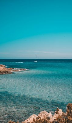 a sailboat is out on the water near some rocks