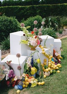 a bunch of flowers that are sitting on some blocks in the grass with eggs around them