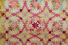 a pink and yellow quilt with flowers on it