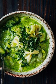 a bowl filled with broccoli and spinach soup on top of a wooden table