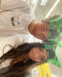 two people standing next to each other in front of a mirror wearing minecraft hats