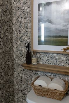 the bathroom is decorated with wallpaper and has a basket on the toilet seat next to it