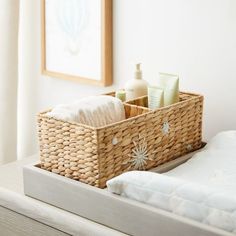 a wicker basket with soap and lotion in it sitting on a white bed