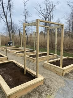 several wooden raised garden beds with fencing around them and dirt on the ground in front