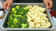 a person is holding a tray with broccoli and cauliflower in it