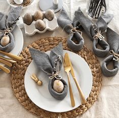 the table is set with silverware and gray napkins, gold utensils