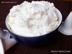 a blue bowl filled with whipped cream next to two spoons on top of a mat