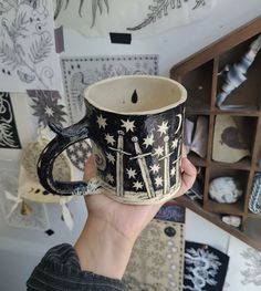 a person holding up a coffee mug with designs on the inside and outside of it