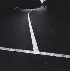 a black and white photo of a street with lines painted on the side of it