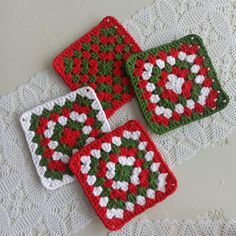 four crocheted coasters are sitting on a doily, one is red and the other is green