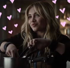 a woman is stirring some food in a pot with hearts drawn on the wall behind her