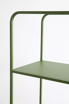 a green shelf sitting on top of a white wall