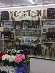 a store display with flowers and chairs in front of it on the wall is a sign that says cotton