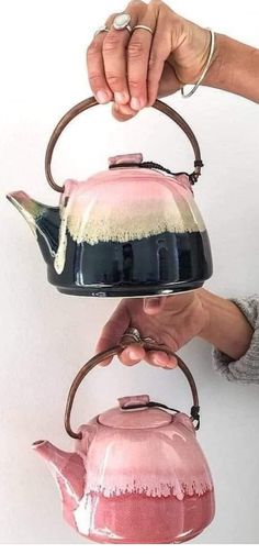 a person holding a pink and black tea kettle