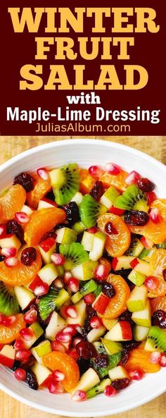 a white bowl filled with fruit salad on top of a wooden table next to an orange and