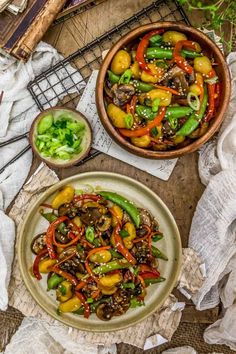 a bowl of stir fry with vegetables on the side next to a plate of broccoli and peppers