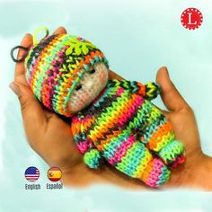 a hand holding a small stuffed animal in a multicolored knitted striped sweater