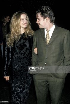 a man in a suit and tie standing next to a woman wearing a black dress