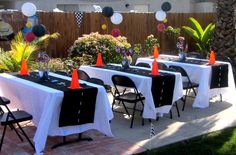 an outdoor party with white tablecloths and black tables topped with orange cone decorations