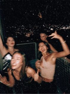 four women are posing for a photo in front of a cityscape at night