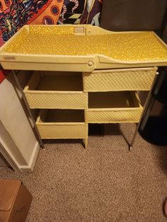 a yellow baby crib with drawers on the floor