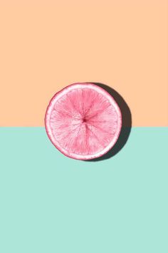 a pink grapefruit cut in half on a pastel background