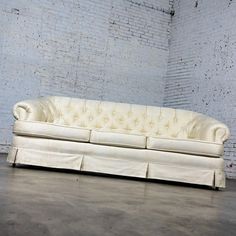 a white couch sitting on top of a hard wood floor next to a brick wall